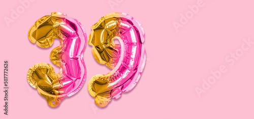 Rainbow foil balloon number, digit thirty nine on a pink background. Birthday greeting card with inscription 39. Top view. Numerical digit. Celebration event, template. Banner photo