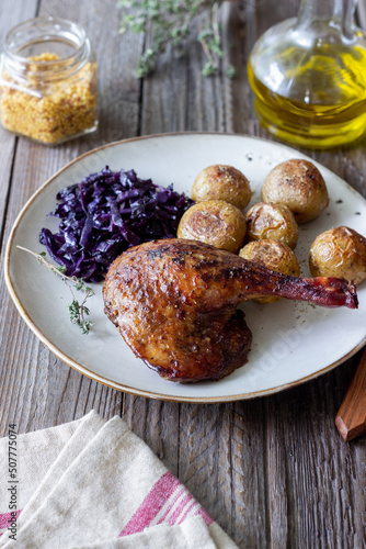 Baked duck leg with potatoes and red cabbage.
