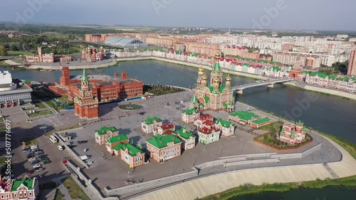 Summer aerial view of golden-domed Orthodox Cathedral of Annunciation of Blessed Virgin, pedestrian bridge across Malaya Kokshaga river and colorful Bruges embankment in Yoshkar-Ola, Mari El, Russia photo