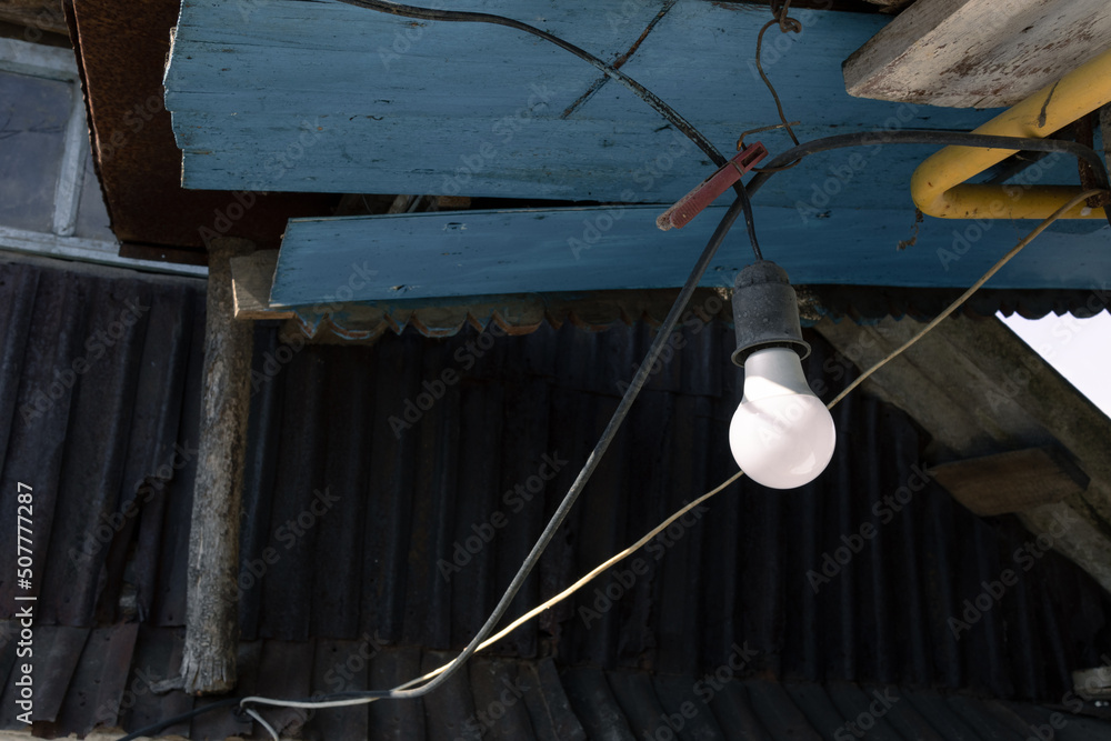 Light bulb under the roof of an old village house
