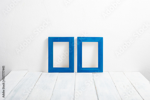 two empty blue picture frames on white wooden table © tstock