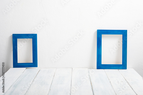 two empty blue picture frames on white wooden table © tstock