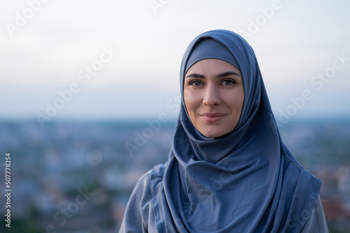 Obraz na płótnie Portrait of a young beautiful girl in a hijab looking at the camera on a backgro