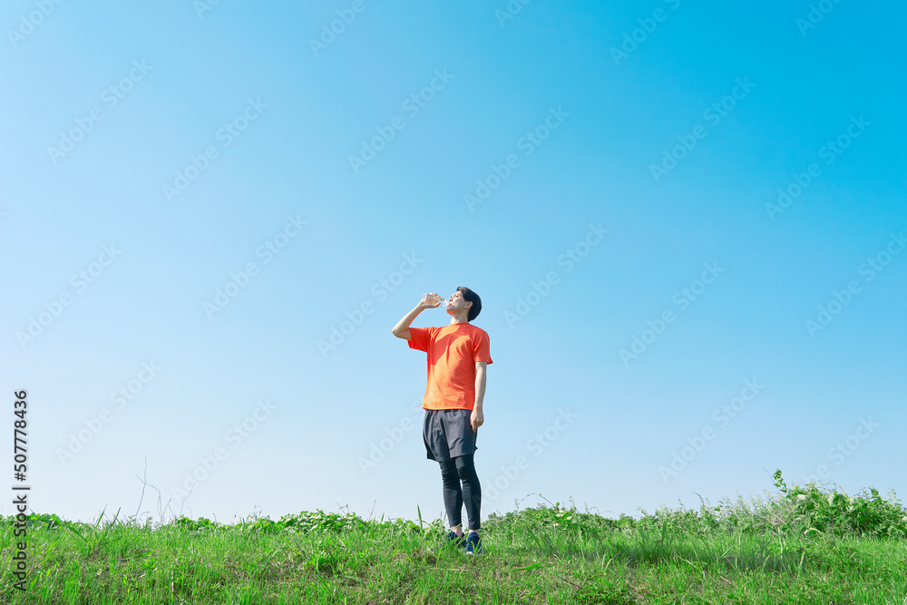屋外でペットボトルの水を飲む運動する男性　コピースペースあり