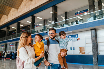 Happy young family with luggage in railroad station go together on vacation.