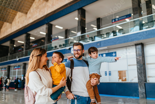 Happy young family with luggage in railroad station go together on vacation.