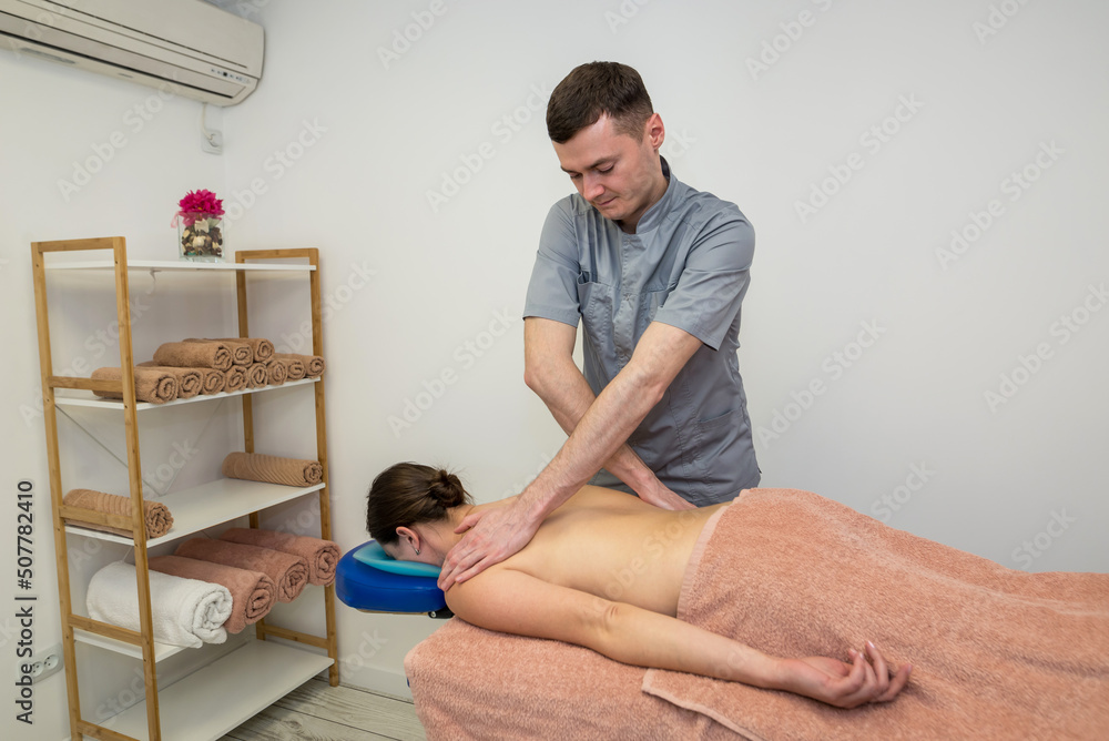 Foto de A woman enjoys a relaxing back and full body massage by a male  massage therapist at a beauty spa. do Stock | Adobe Stock