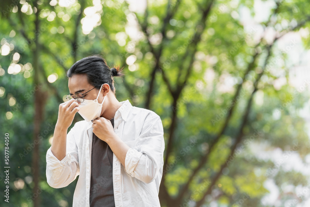 Asian young man is wearing a mask outdoors Asian young man is wearing a mask outdoors