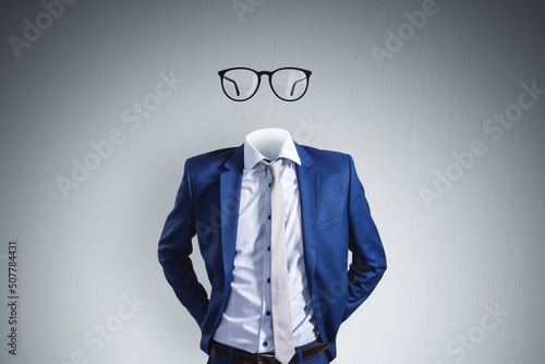 Headless invisible businessman with abstract glasses standing on gray wall background. Business and secret concept.
