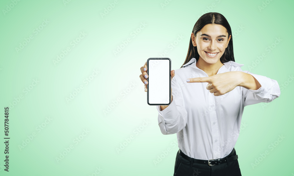 Mobile application concept with happy girl in white shirt showing modern cellphone with white blank screen on abstract light green background with place for your logo or text, mockup Mobile application concept with happy girl in white shirt showing modern cellphone with white blank screen on abstract light green background with place for your logo or text, mockup