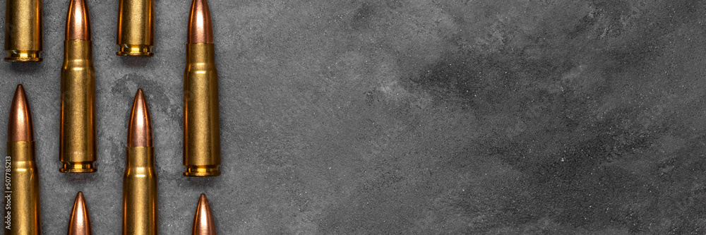 Bullets on gray background banner with copy space. Cartridges 7.62 caliber for Kalashnikov assault rifle. Panoramic web header. Wide screen wallpaper Bullets on gray background banner with copy space. Cartridges 7.62 caliber for Kalashnikov assault rifle. Panoramic web header. Wide screen wallpaper