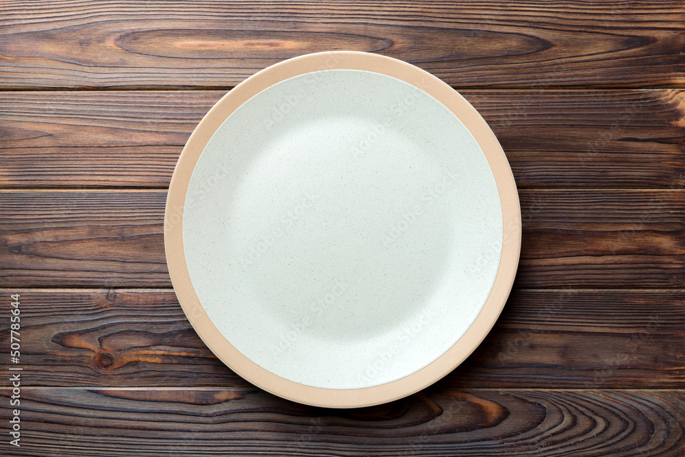 Top view of empty light plate on wooden background. Empty space for your design Top view of empty light plate on wooden background. Empty space for your design