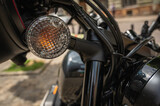 a motorcycle parked on the sidewalk with a blurred city street with cars in the background, selective focus