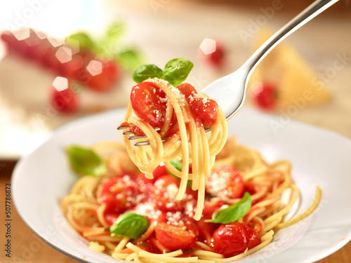 Quadro su tela Nudeln Parmesan Tomatensauce auf Gabel über einem Spaghettiteller Tomaten unscha
