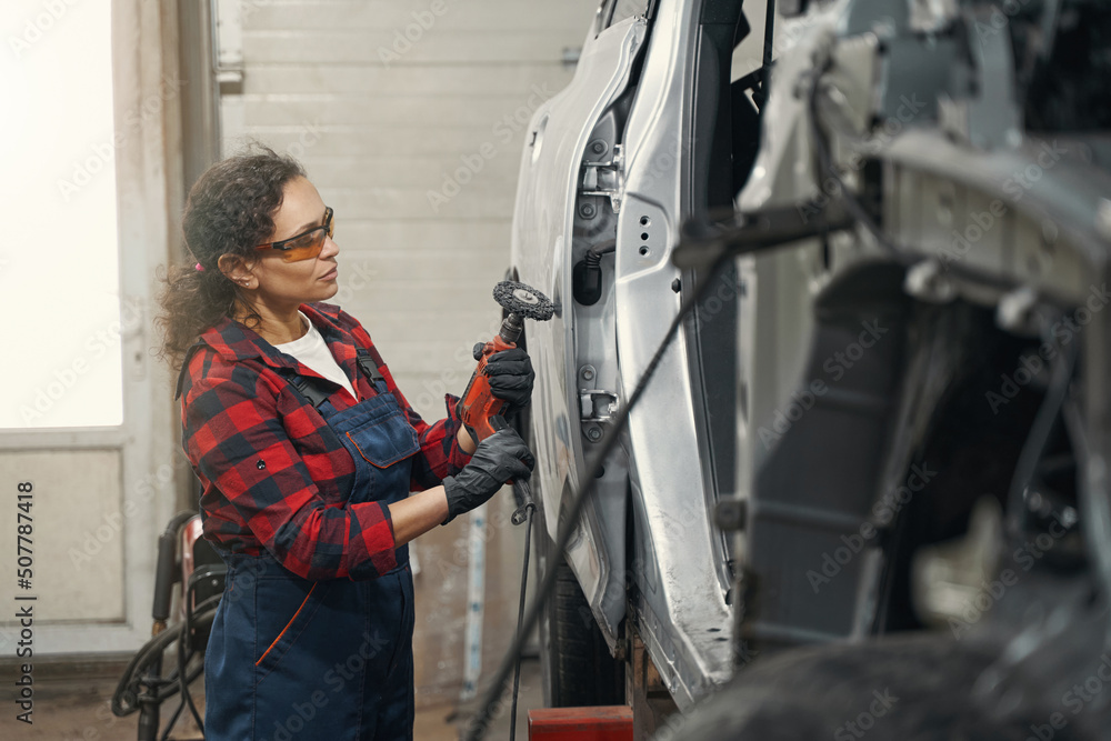 Female auto mechanic repairing car in auto service garage Female auto mechanic repairing car in auto service garage