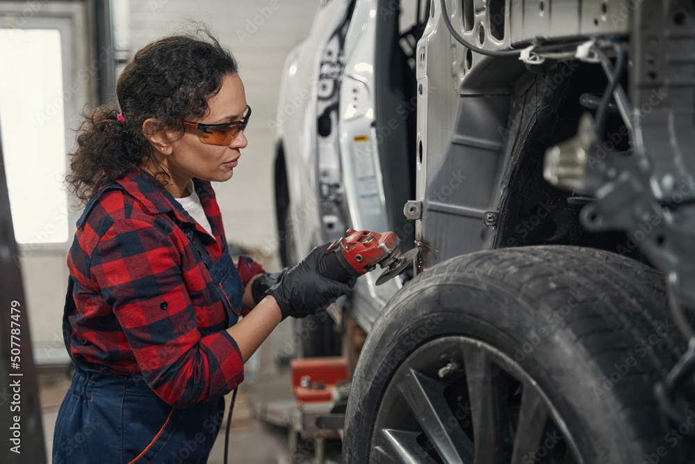 Woman auto mechanic repairing car at repair service station