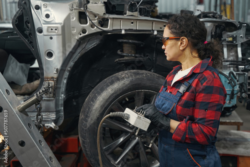 Woman mechanic using diagnostic equipment in auto repair shop