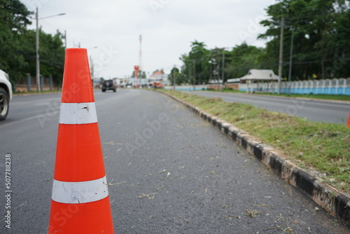Red rubber cone and blurry background image of road maintenance agency work. © suwichan