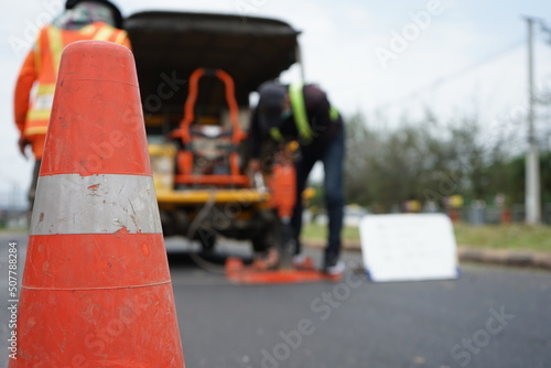 Red rubber cone and blurry background image of road maintenance agency work.