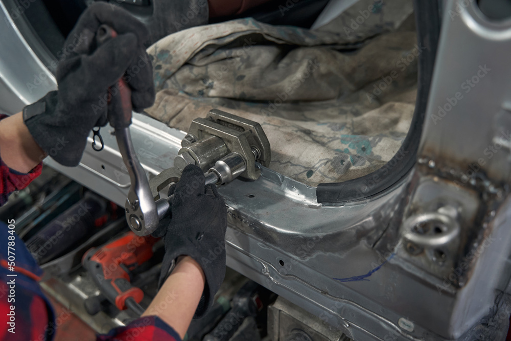 Female auto mechanic repairing car in automobile garage Female auto mechanic repairing car in automobile garage