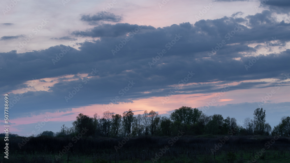 Big clouds above forest at twilight, calm natural landscape Big clouds above forest at twilight, calm natural landscape