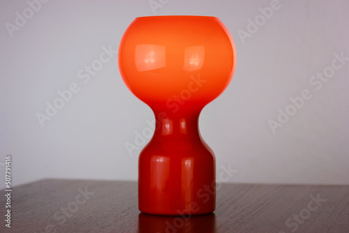 A 60s modern orange bedside lamp with glass spaceage vintage midcentury design front side view isolated on white background with warm orange light in the studio living room creative HQ 60s furniture 