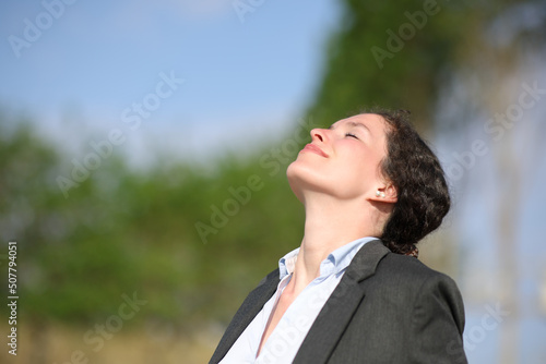 Businesswoman relaxing breathing fresh air in a park