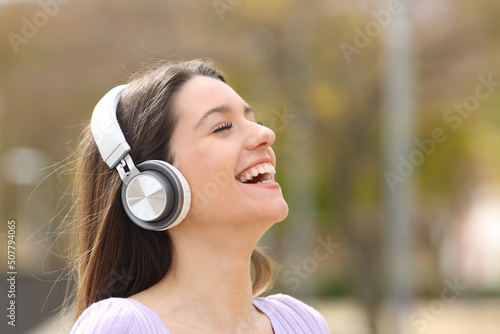 Happy teen listening to music laughing in a park