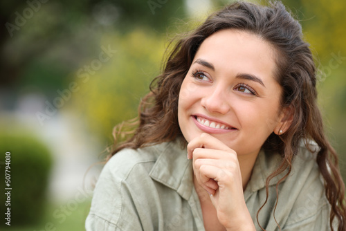 Pensive woman looks at side wondering in a park