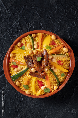 Meat and vegetable couscous, festive Arabic food with chickpeas, on a dark background, shot from above