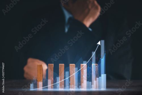 Businessman in suite showing rising sign Stock chart with graph indicator. financial data exchange