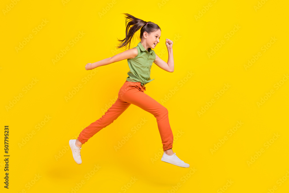 Photo of funky pretty student girl wear green shirt smiling running fast jumping high isolated yellow color background