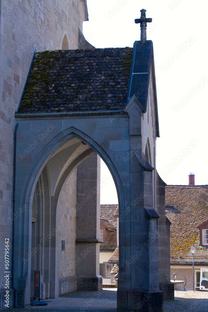 Fototapeta premium Entrance of medieval church named Pfarrkirche St. Johann with stone cross at the old town of City of Rapperswil-Jona on a sunny spring day. Photo taken April 28th, 2022, Rapperswil-Jona, Switzerland.