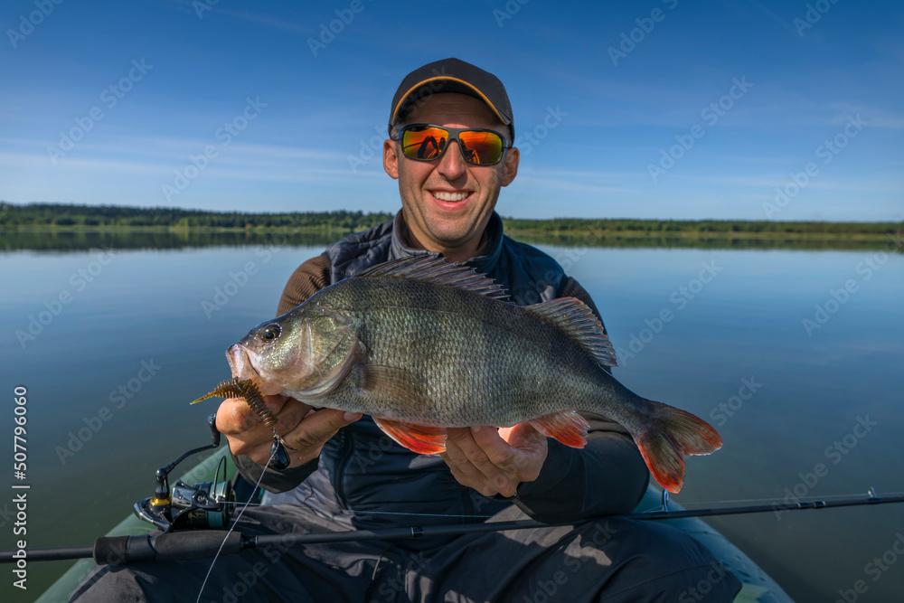 Successful perch fishing. Smiling fisherman with big perch fish on boat Successful perch fishing. Smiling fisherman with big perch fish on boat
