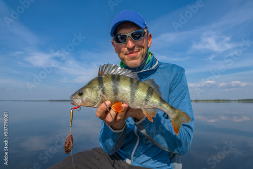 Perch fishing. Fisherman holds perch fish at lake