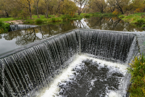 Dam sluice on small river. Gateway channel with waterfall