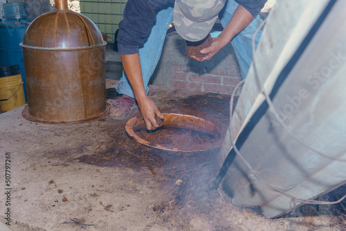 Mezcal master pouring the extract of the agave pineapples photo