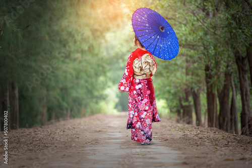 Fototapet Thai girl wearing a kimono stands in the way of a tunnel searching for wood
