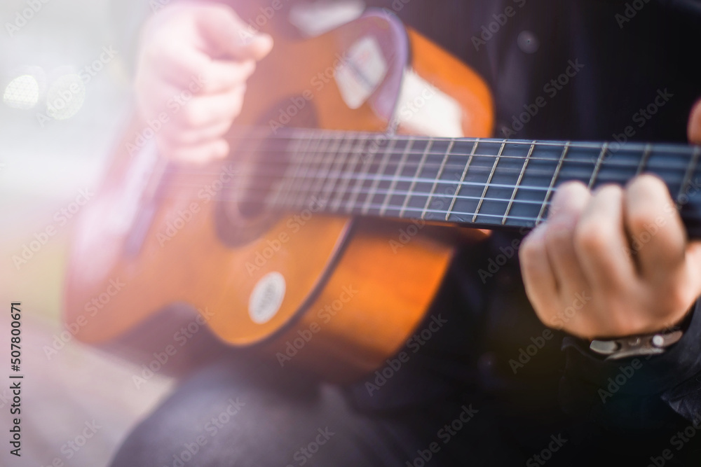 Fototapeta premium Street musician. A man plays the guitar on a city street.