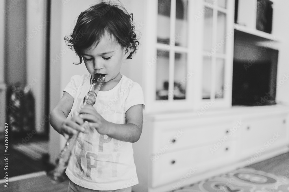 Portrait of a toddler, girl, adorable baby playing reed pipe, panpipe ...