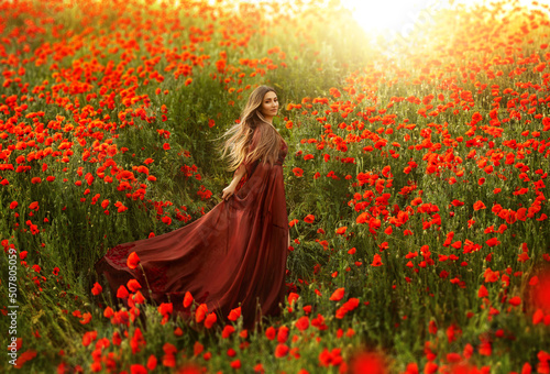Billede på lærred Happy fantasy woman queen in red silk dress, walking in poppy field, summer green grass, nature flowers
