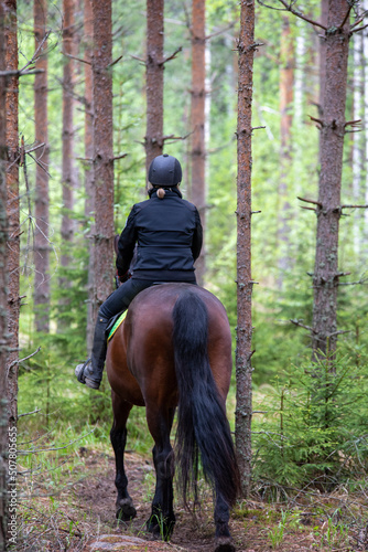 Woman horseback riding in forest path © citikka