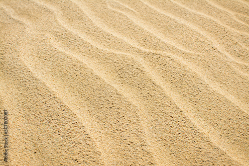 Close up top view of sand dune surface with ripple patterns formed by wind.