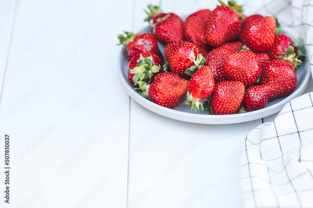 Delicious, fresh strawberries in a stylish plate on a white wooden background. Top view with space to copy. Delicious, fresh strawberries in a stylish plate on a white wooden background. Top view with space to copy.