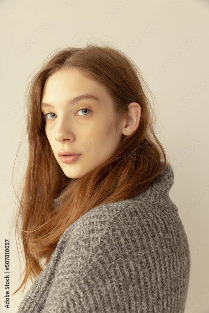 Portrait of beautiful young girl with nude make up posing, looking at camera isolated over grey studio background. Natural beauty Portrait of beautiful young girl with nude make up posing, looking at camera isolated over grey studio background. Natural beauty
