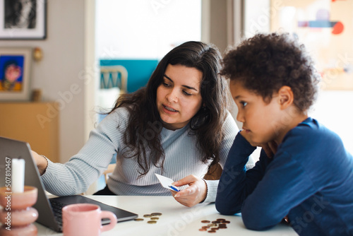 Mother teaching online payment to son on laptop at home photo