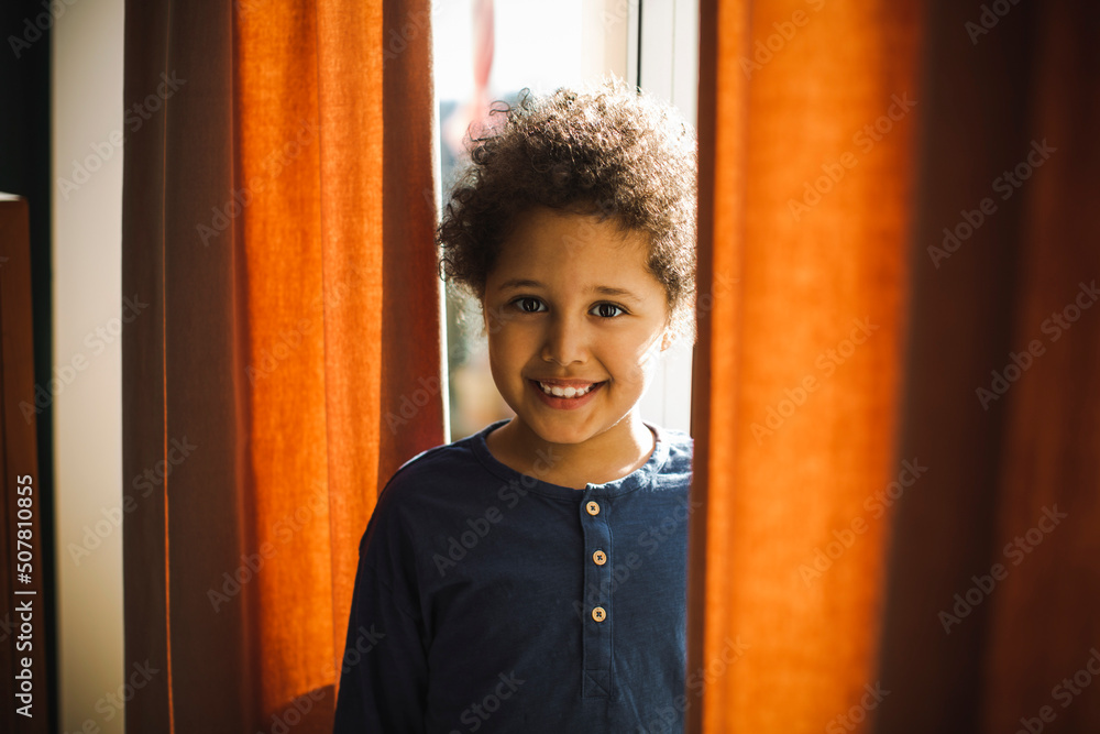 Portrait of smiling boy standing behind curtain at home Stock Photo ...