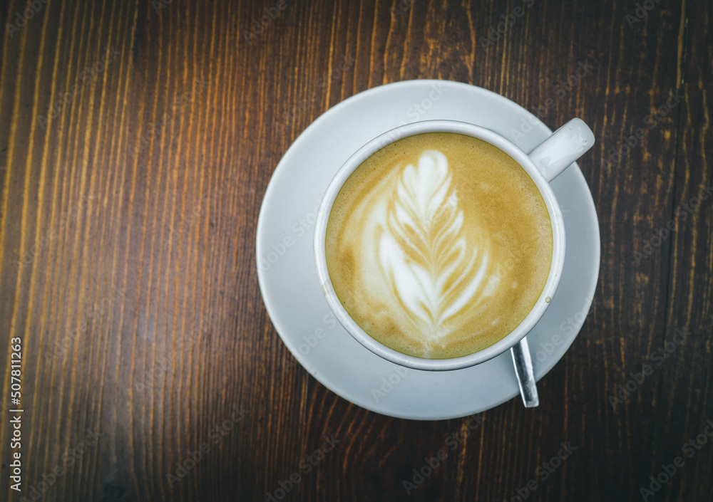 There is a cup of coffee on a wooden brown table during the day There is a cup of coffee on a wooden brown table during the day