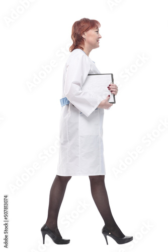 competent female doctor with clipboard striding forward .