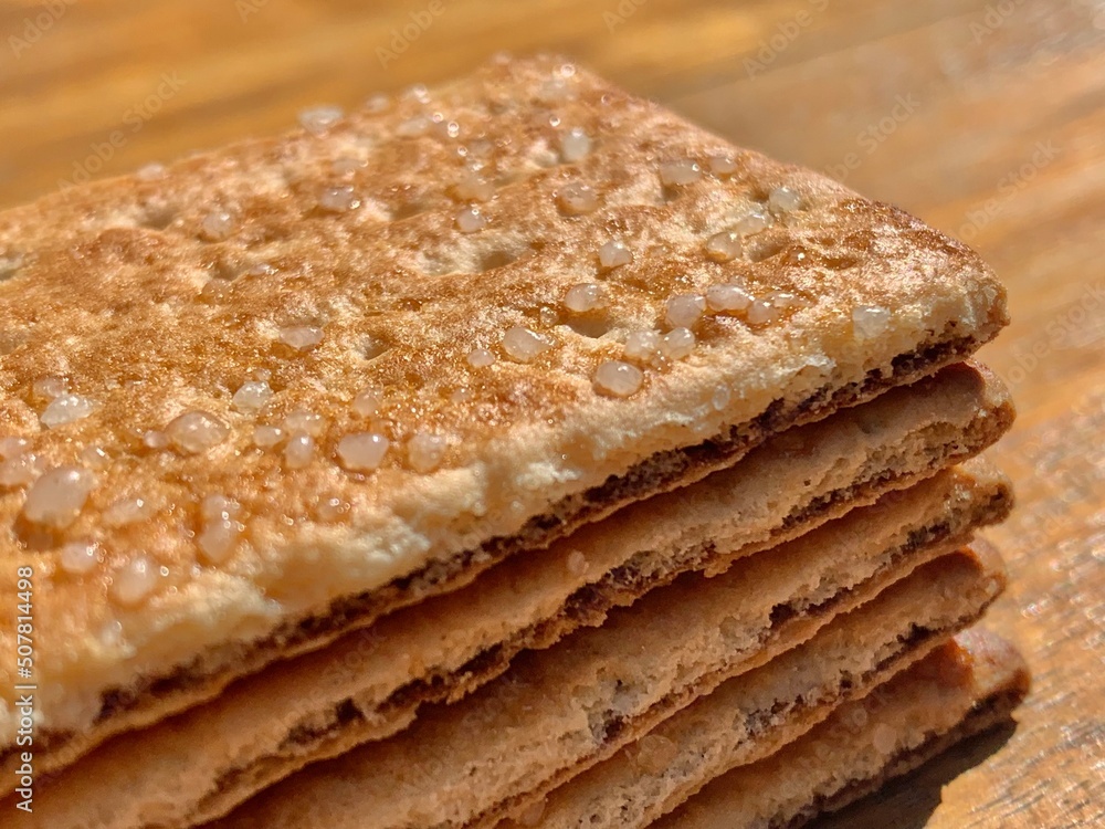 Stacks of the crunchy crisp bread biscuits with granulated sugar on the wood table with closeup shot and natural lighting Stacks of the crunchy crisp bread biscuits with granulated sugar on the wood table with closeup shot and natural lighting